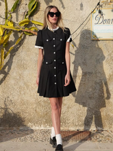 a lady wears a little black dress with pearl buttons